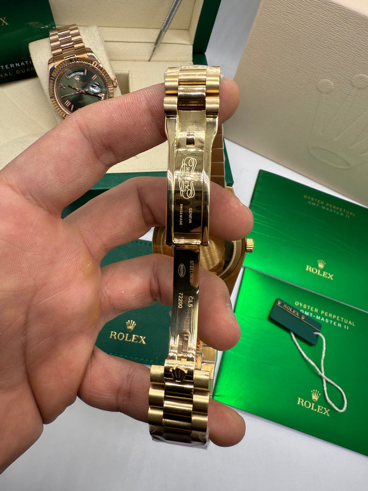 Relógio Rolex dourado com fecho da pulseira e caixa lateral, mostrador verde.