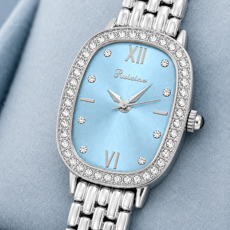 Relógio oval com pulseira metálica prateada e mostrador azul claro com cristais