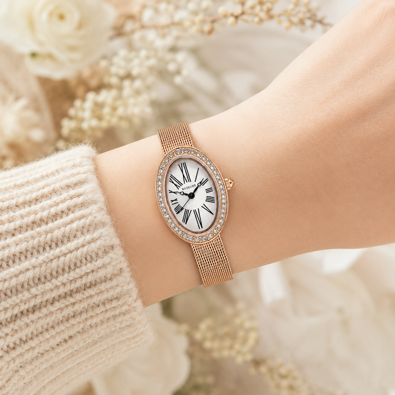 Relógio oval dourado rosé com pulseira de malha e mostrador com algarismos romanos