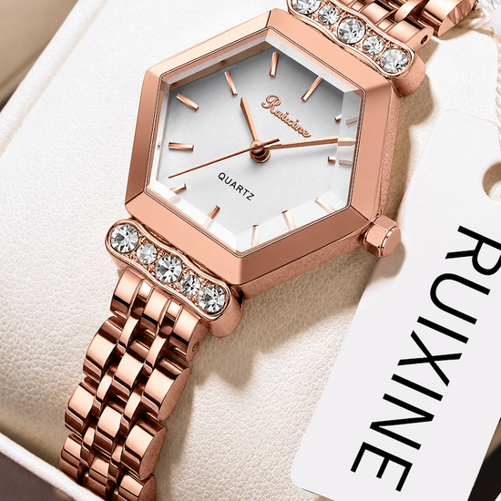Relógio rosé com mostrador branco, aro hexagonal e pulseira metálica detalhada