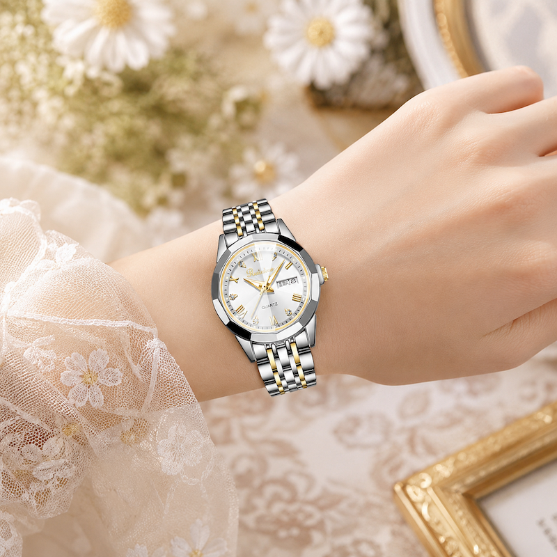 Relógio prateado e dourado no pulso, mostrador branco e bracelete metálico