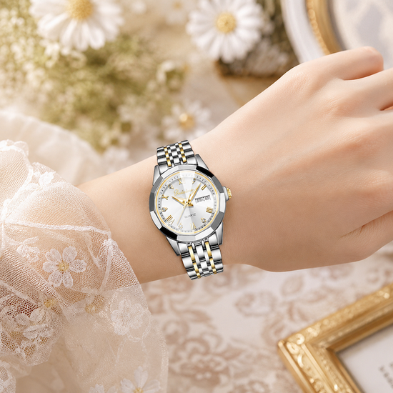Relógio prateado e dourado no pulso, mostrador branco e bracelete metálico