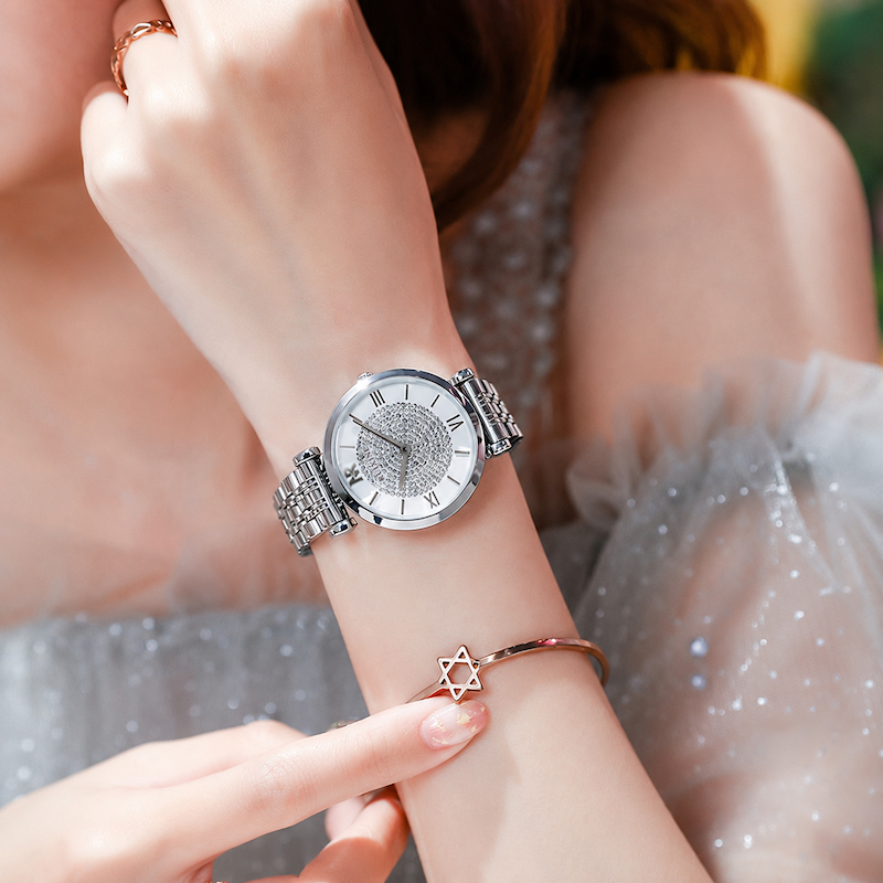 Relógio Estrela no pulso, mostrador branco com detalhes rosé e pulseira prateada