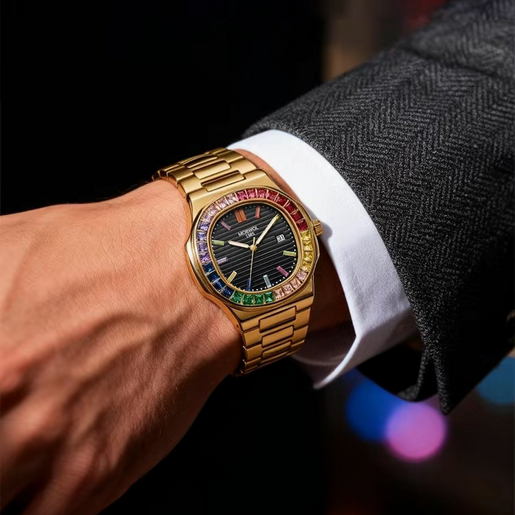 Relógio dourado no pulso, mostrador preto e aro multicolorido com pulseira metálica.