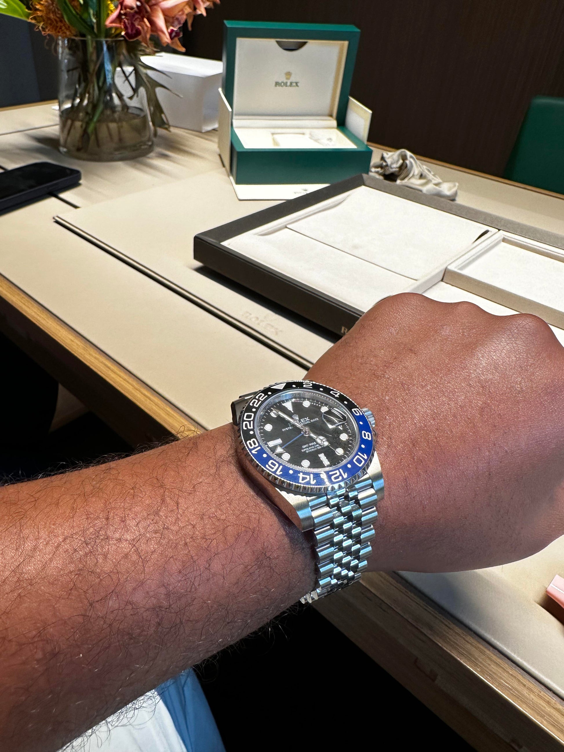 Relógio automático Rolex no pulso com mostrador preto e moldura azul