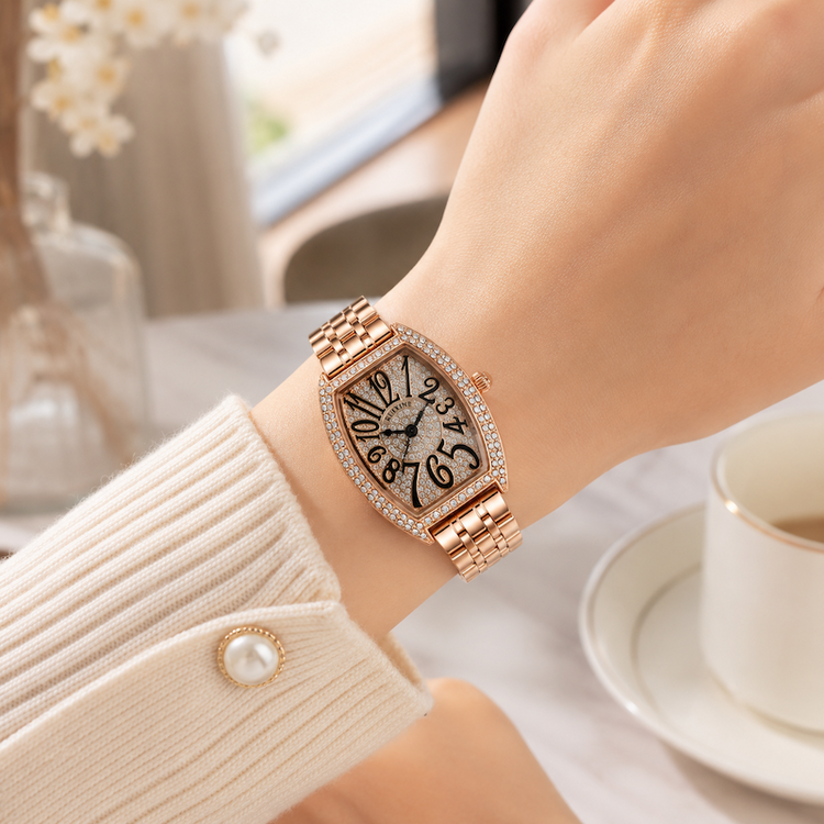 Relógio rosé no pulso, mostrador preto com números arábicos e pulseira metálica