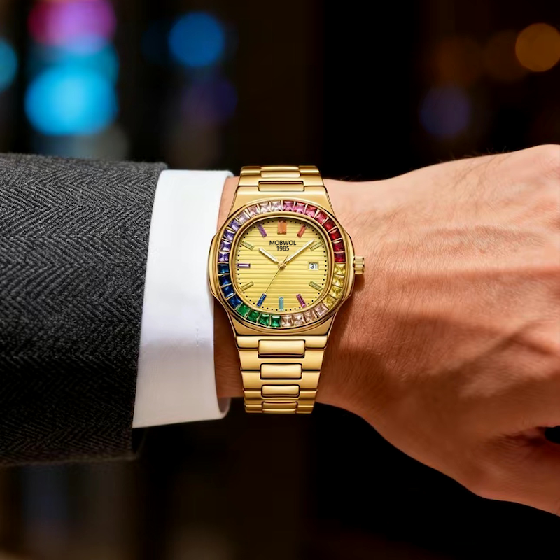 Relógio dourado no pulso com mostrador bege e aro multicolorido na pulseira metálica.