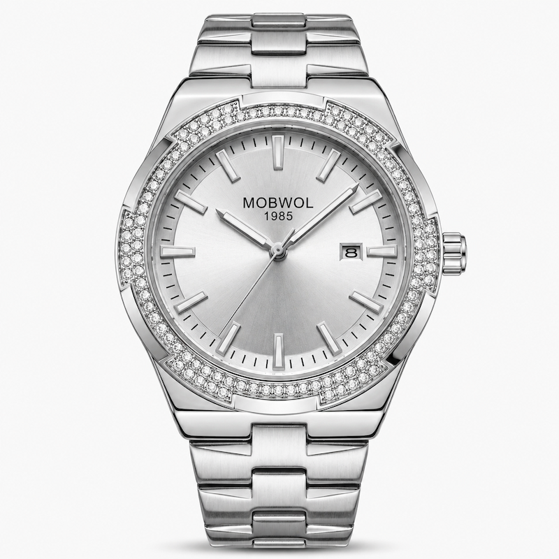 Relógio prateado com mostrador branco e pulseira de aço; moldura cravejada de pedras