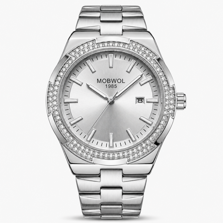 Relógio prateado com mostrador branco e pulseira de aço; moldura cravejada de pedras