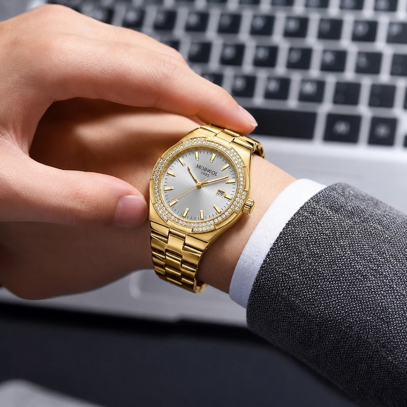 Relógio dourado no pulso, mostrador claro com marcadores; pulseira de aço