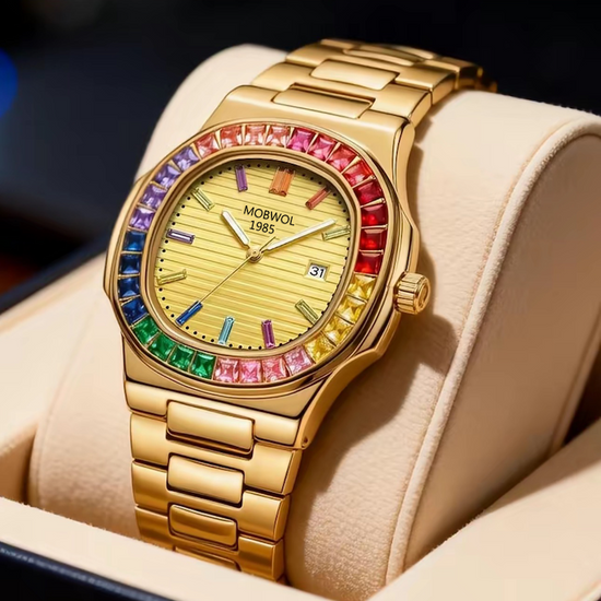 Relógio dourado no pulso com mostrador bege, aro multicolorido e pulseira metálica.