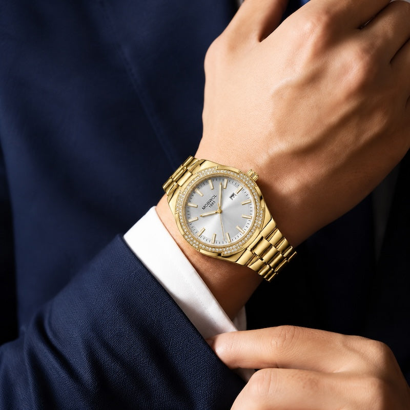 Relógio dourado no pulso, mostrador branco e pulseira de aço com detalhes cravejados
