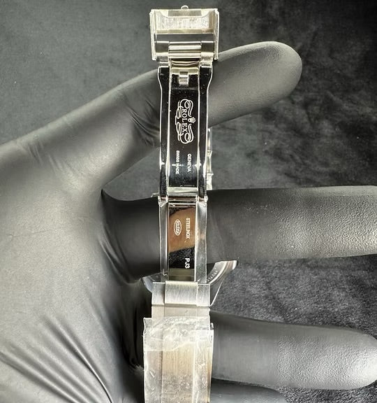 Relógio automático com pulseira de aço, visto pela traseira com fecho metálico.