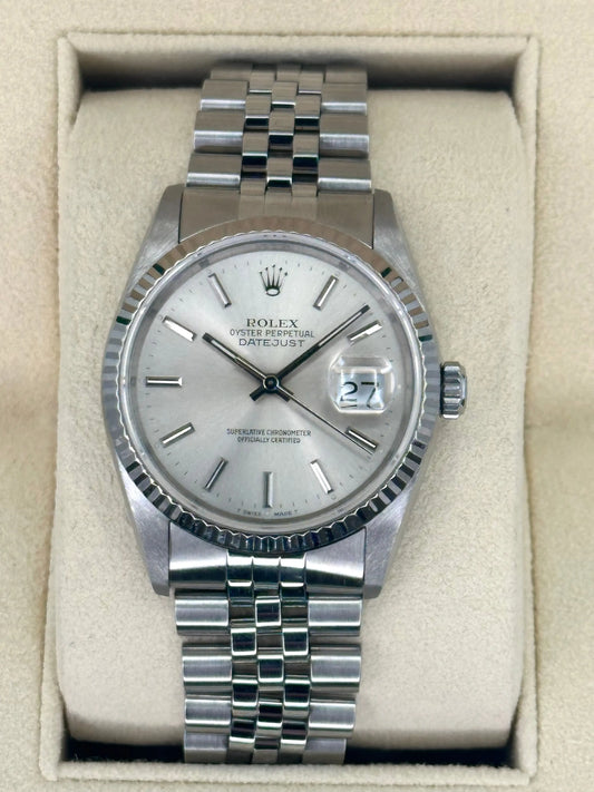 Relógio Rolex prateado com mostrador branco e pulseira metálica, na caixa.