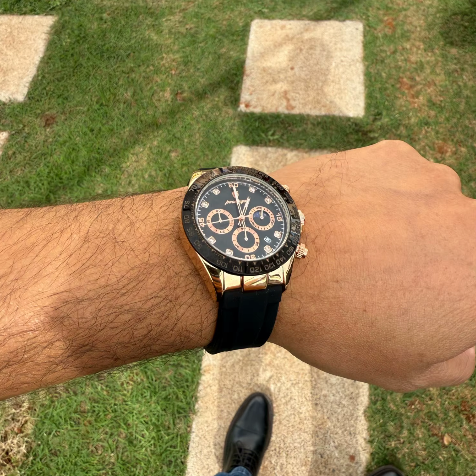 Relógio com mostrador escuro, caixa dourada e pulseira de silicone preta.