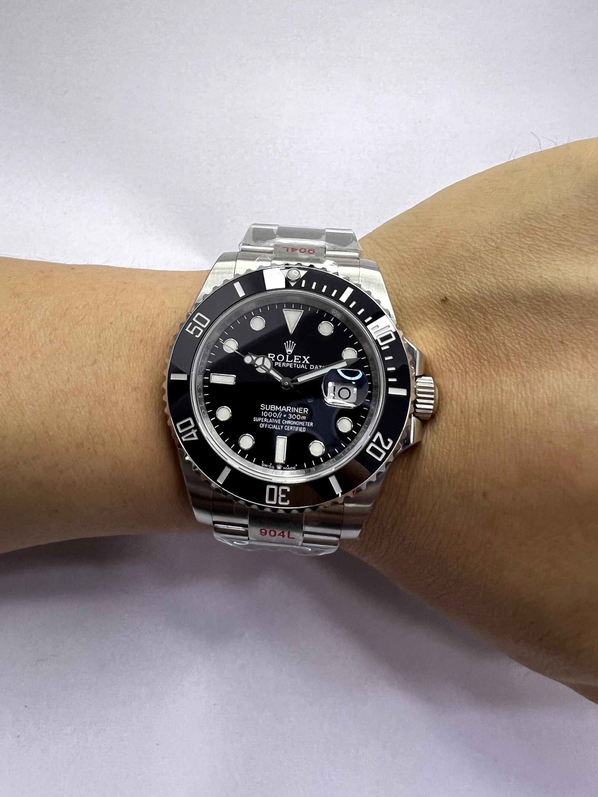 Relógio Rolex com mostrador preto e pulseira de aço no pulso