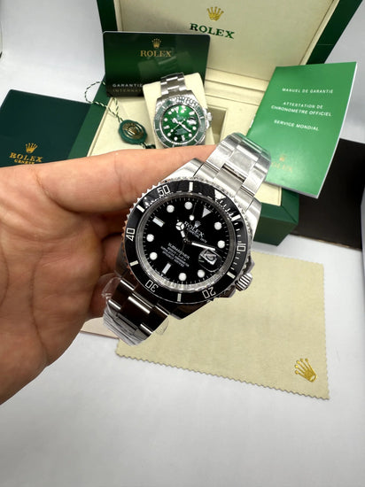 Relógio Rolex Submariner Date automático em mãos, pulseira de aço e cartões verdes ao fundo