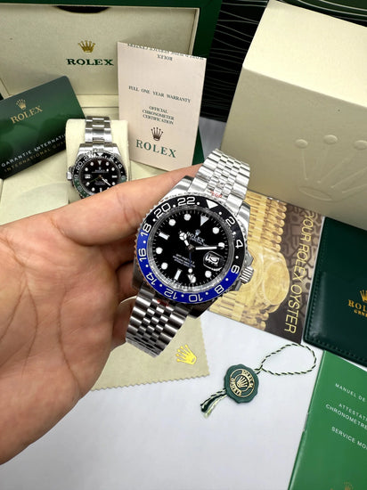 Relógio automático Rolex na mão, mostrador preto e moldura azul, pulseira de aço