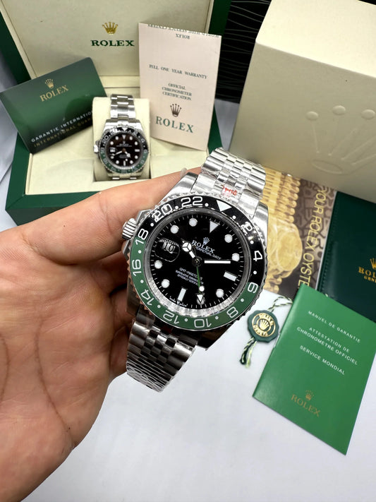 Relógio Rolex GMT Master II na mão, mostrador preto, aro verde e pulseira de aço