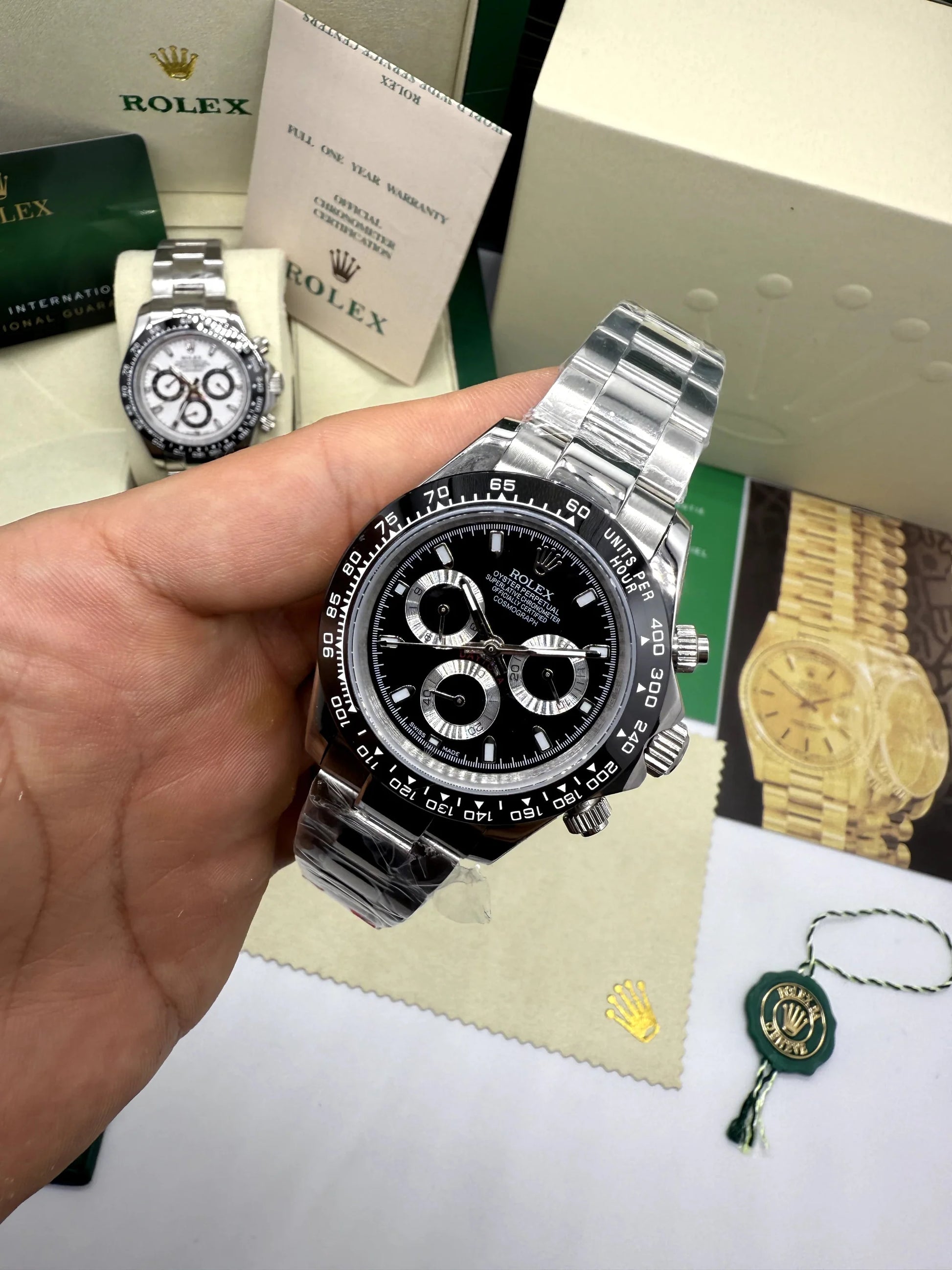 Relógio automático com mostrador preto e cronógrafo, pulseira de aço prateado ao lado