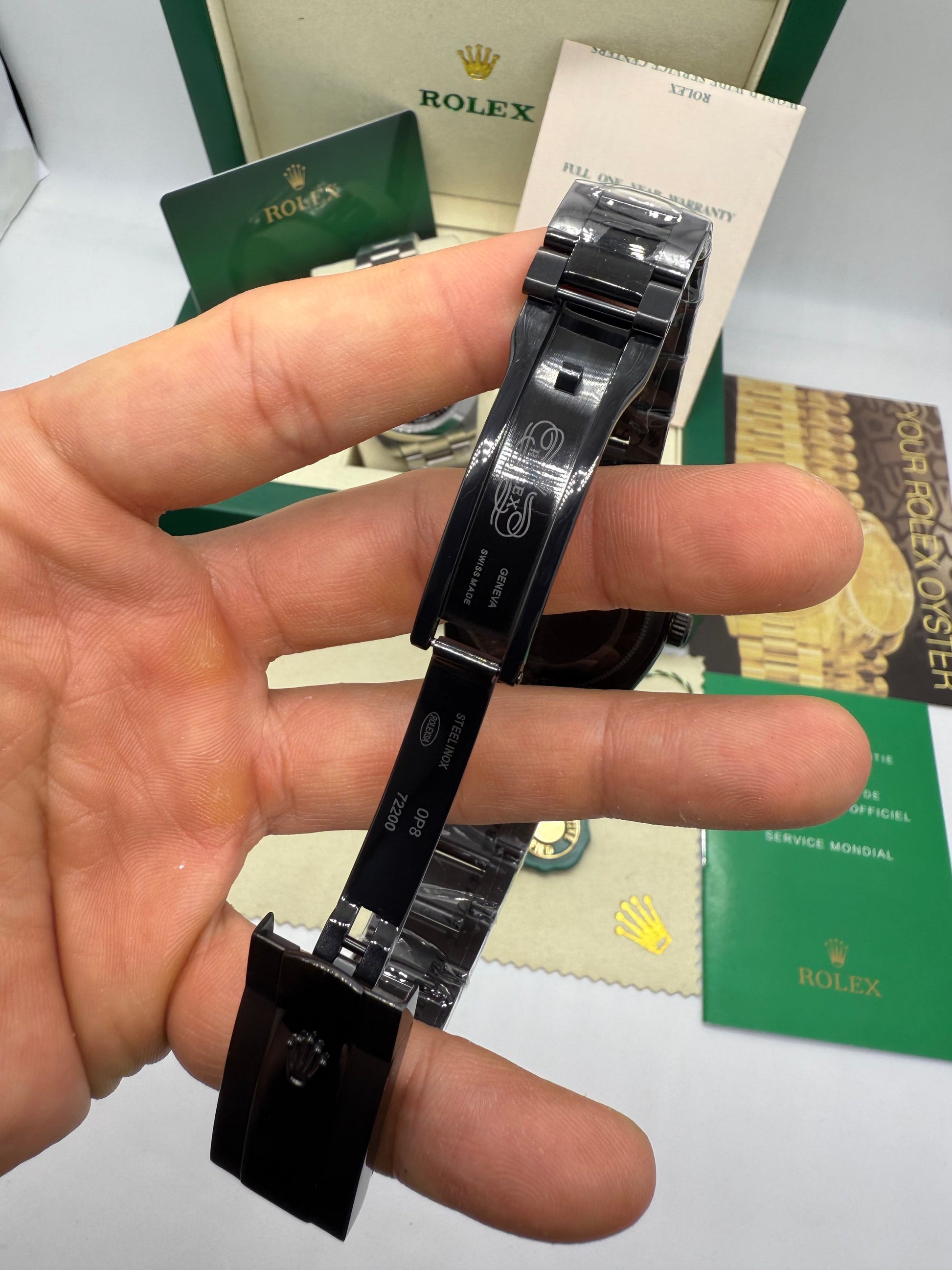 Relógio preto com pulseira de aço e fecho, vista traseira