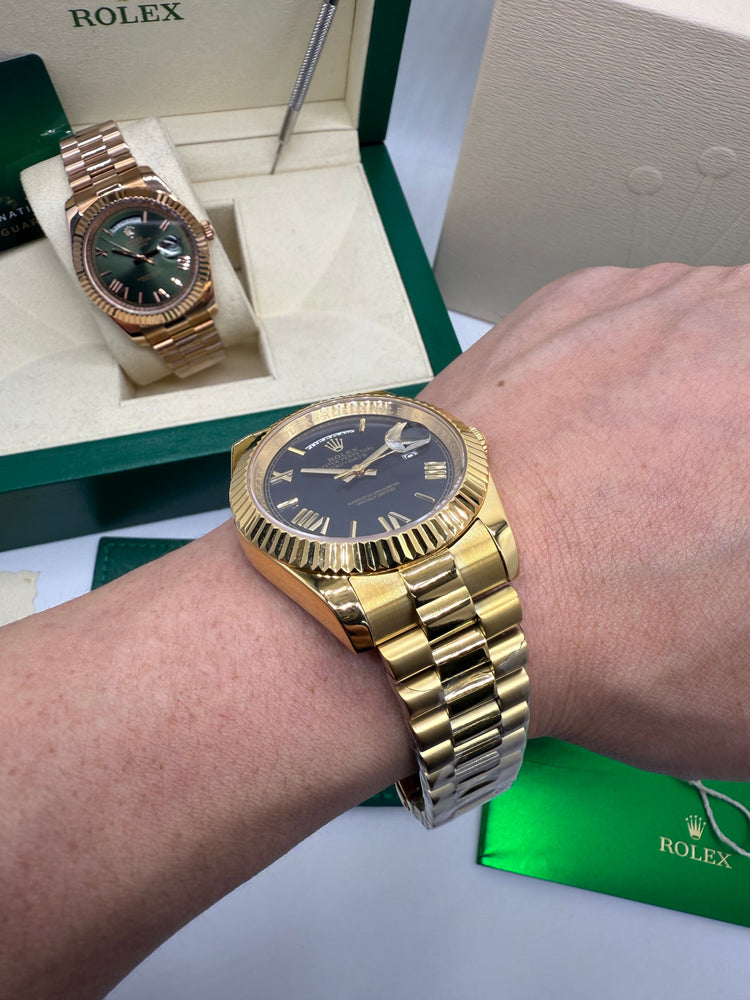 Relógio dourado com mostrador escuro e pulseira de metal no pulso