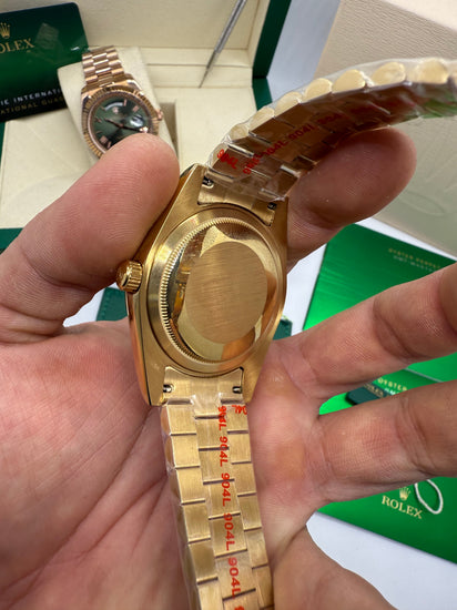 Relógio Rolex dourado com fundo traseiro e marcações na pulseira metálica.