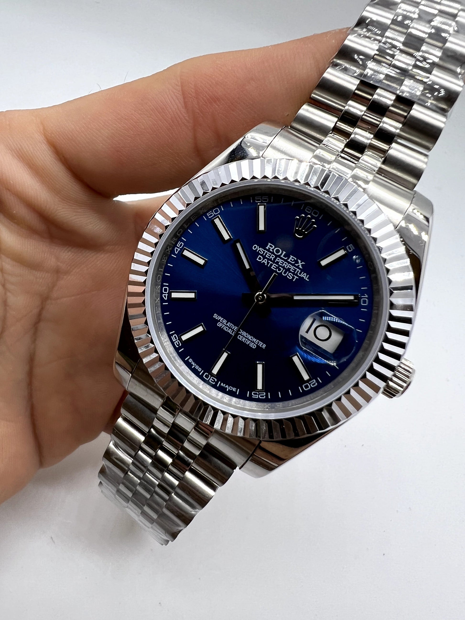 Relógio Rolex com mostrador azul e luneta canelada, pulseira de aço prateada