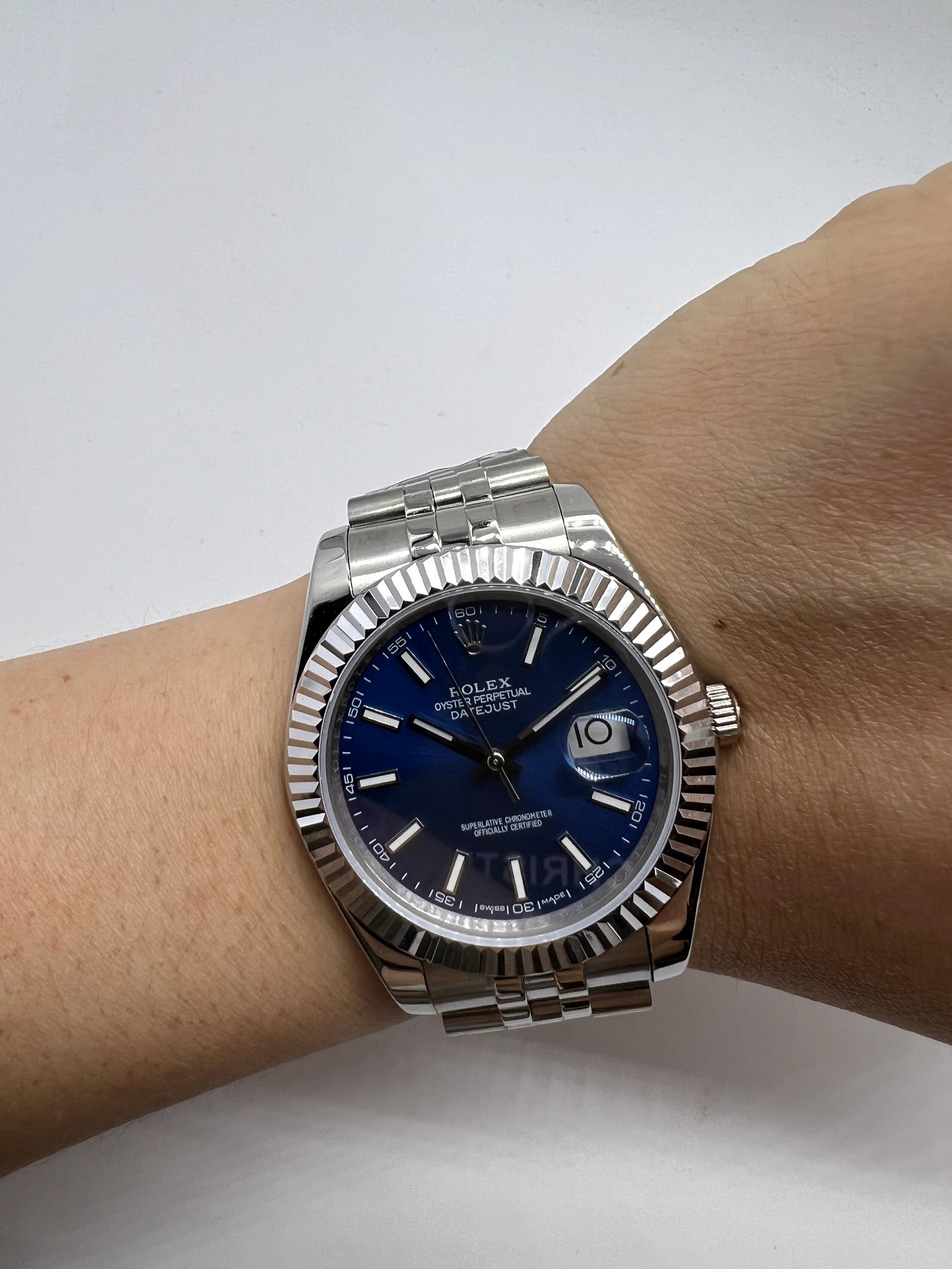 Relógio Rolex Date Just no pulso, mostrador azul e pulseira metálica prateada