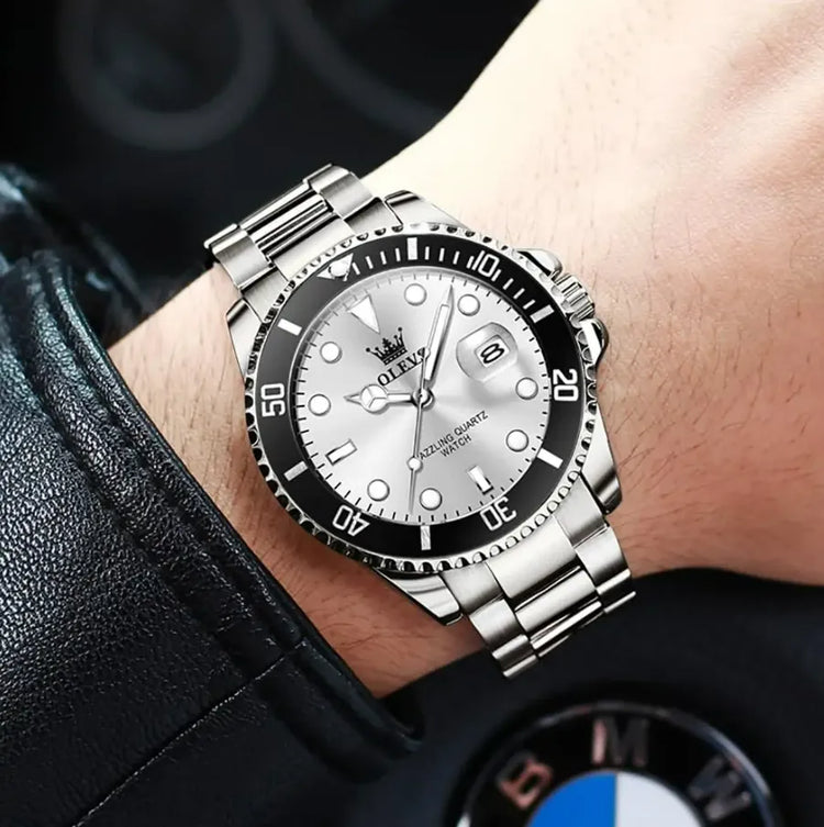 Relógio prateado com pulseira metálica, mostrador branco e janela de data no visor