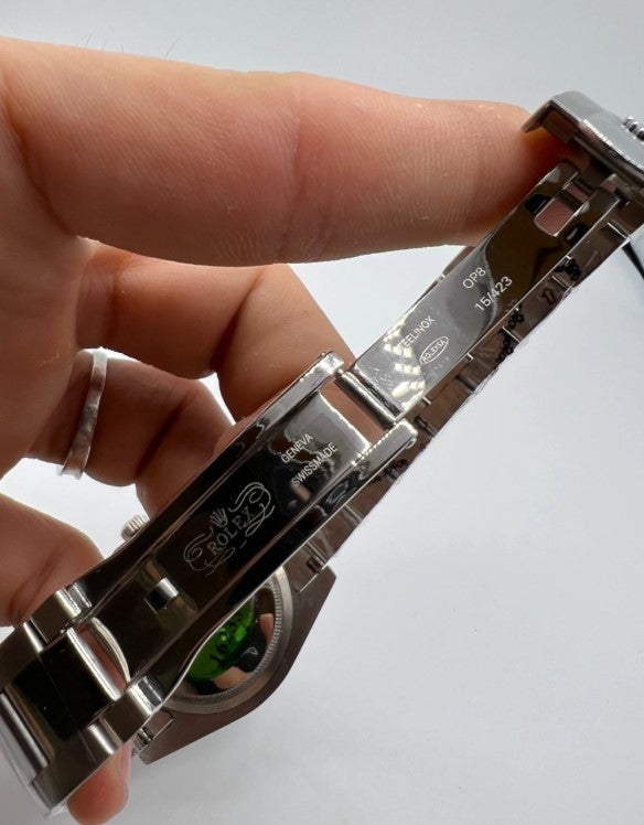 Fecho da pulseira do relógio de aço com detalhe gravado, em mãos