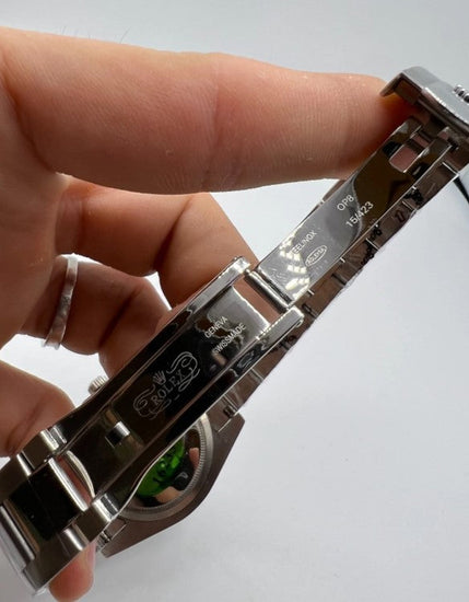 Fecho da pulseira do relógio de aço com detalhe gravado, em mãos