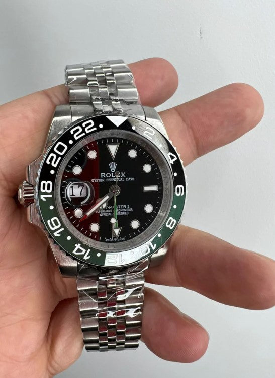 Relógio Rolex GMT Master II na mão, mostrador preto e aro verde com pulseira metálica