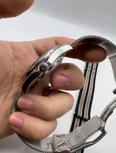 Caixa de aço do relógio Omega com coroa e pulseira metálica em mão