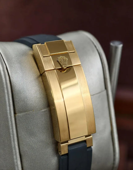 Pulseira do relógio Rolex com fecho dourado retangular, sobre base clara.
