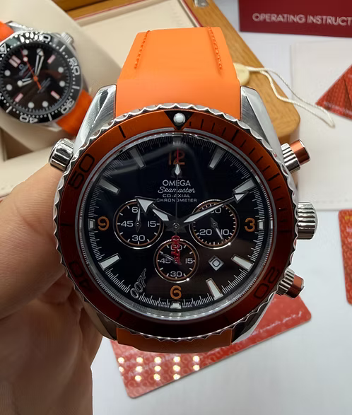 Relógio Omega com mostrador preto, pulseira laranja e botões/coroas laterais em aço
