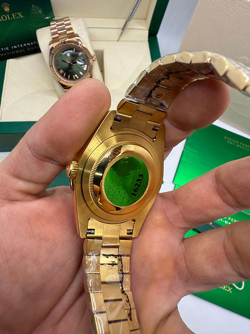 Relógio dourado traseiro com pulseira de metal na mão, fecho visível
