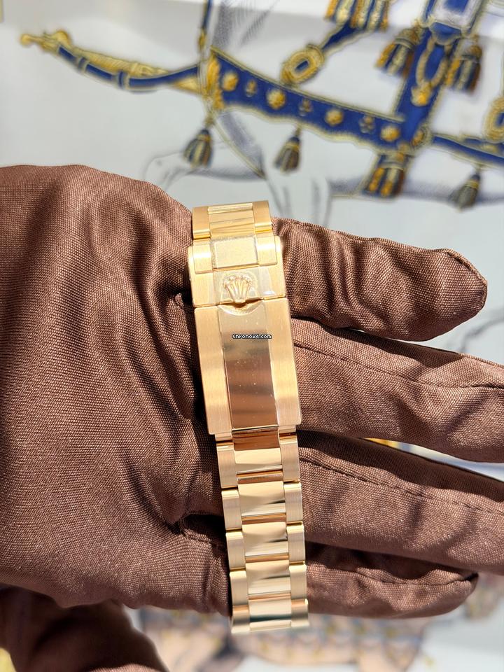 Relógio automático com pulseira dourada em punho, mostrador verde ao fundo