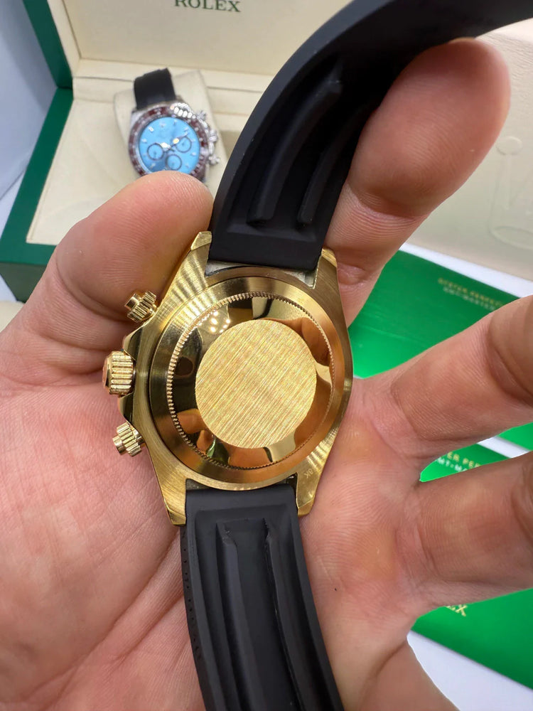 Parte traseira e laterais do relógio Rolex Daytona em ouro com pulseira azul escura.