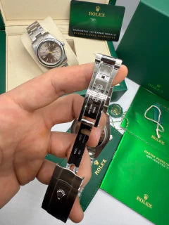 Relógio Rolex com pulseira de aço e fecho, mostrador preto parcialmente visível