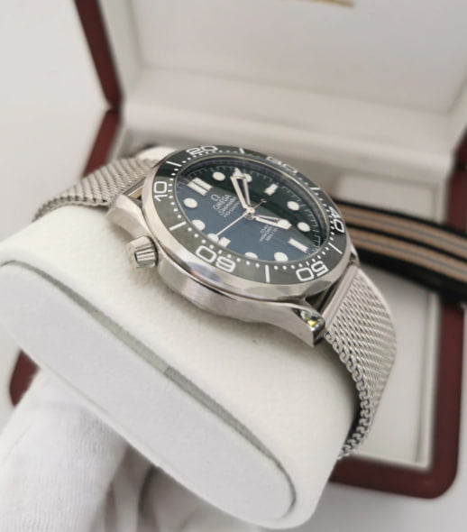 Relógio Omega com mostrador azul, coroa lateral e pulseira de aço em malha