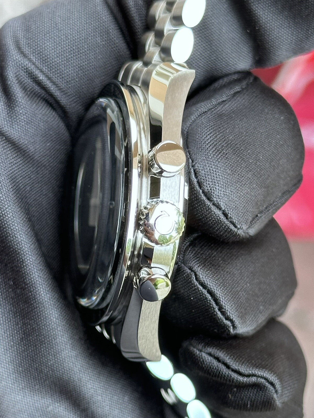 Relógio Omega Speedmaster em vista lateral com botões e pulseira metálica