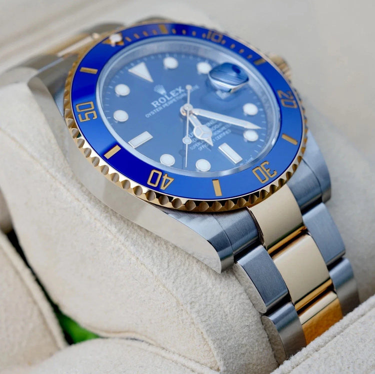 Relógio Rolex Submariner com luneta azul e pulseira bicolor aço e dourado, close.